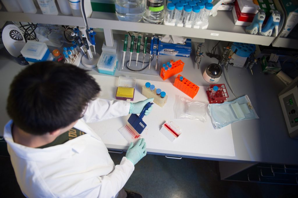Male student in laboratory using pipette.