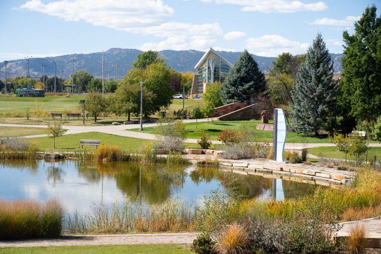 Photo of CSU Lagoon with Rec Center and mountains in background.