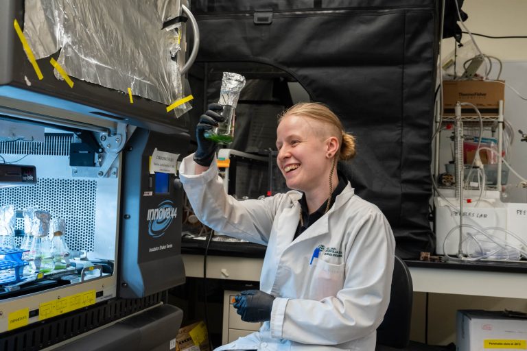 CSU graduate student Darcy Hunstiger poses with her AAAS award and experiments in Professor Christie Peebles' lab in the Suzanne and Walter Scott, Jr. Bioengineering Building, August 2, 2024.