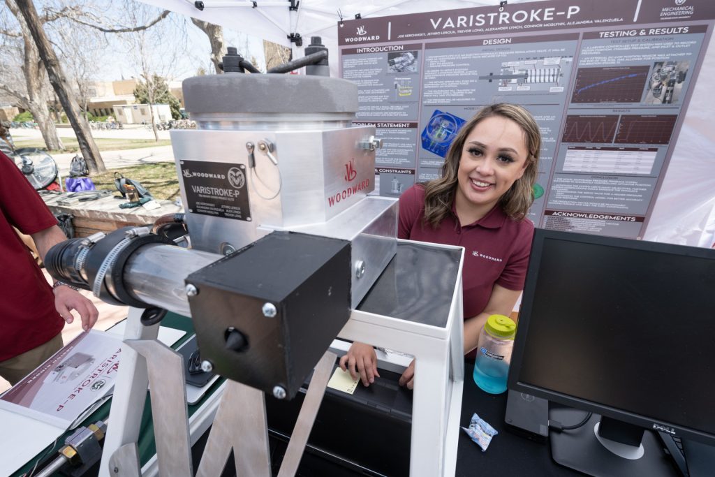 A student stands behind a table with experiments outside at the E-Days event.