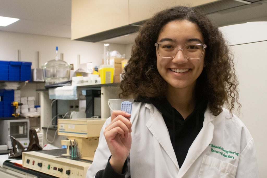 A student holds up a vial in a lab.