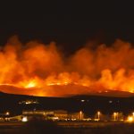 Wildfire burning at night in Northern Nevada with smoke and flames. Shutterstock license through Hussam Mahmoud.