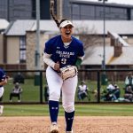 Female in softball uniform cheers from pitcher’s mound.