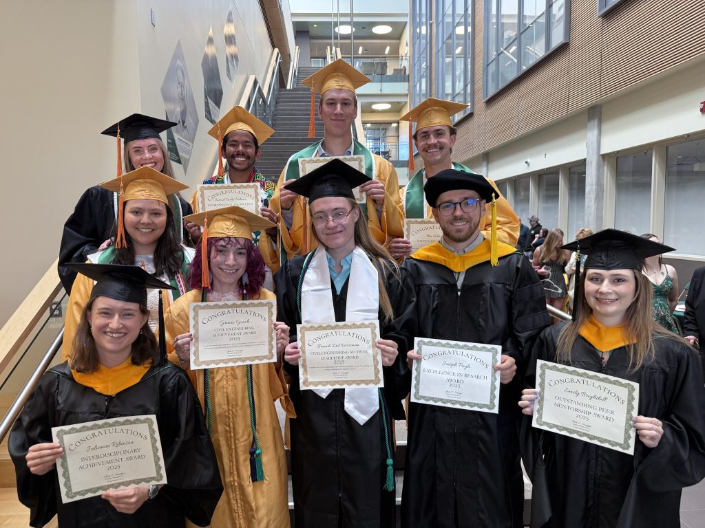 Students in graduation regalia holding certificates.