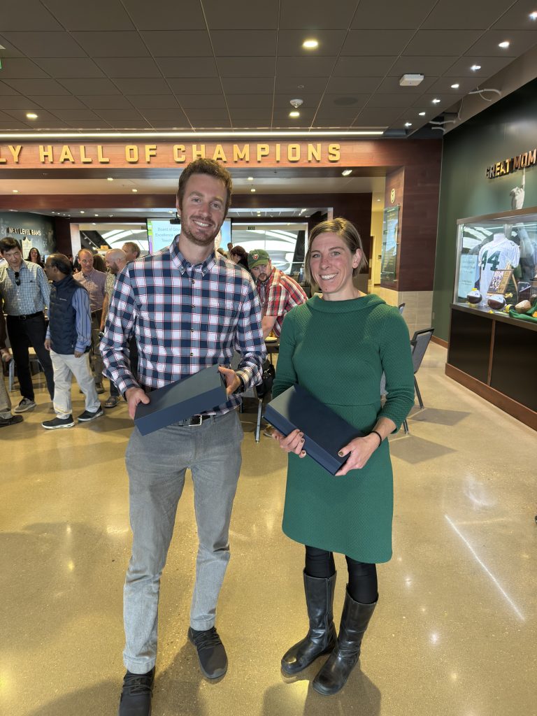Two faculty stand holding awards.