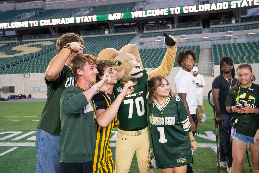 Ram mascot taking selfie with students.