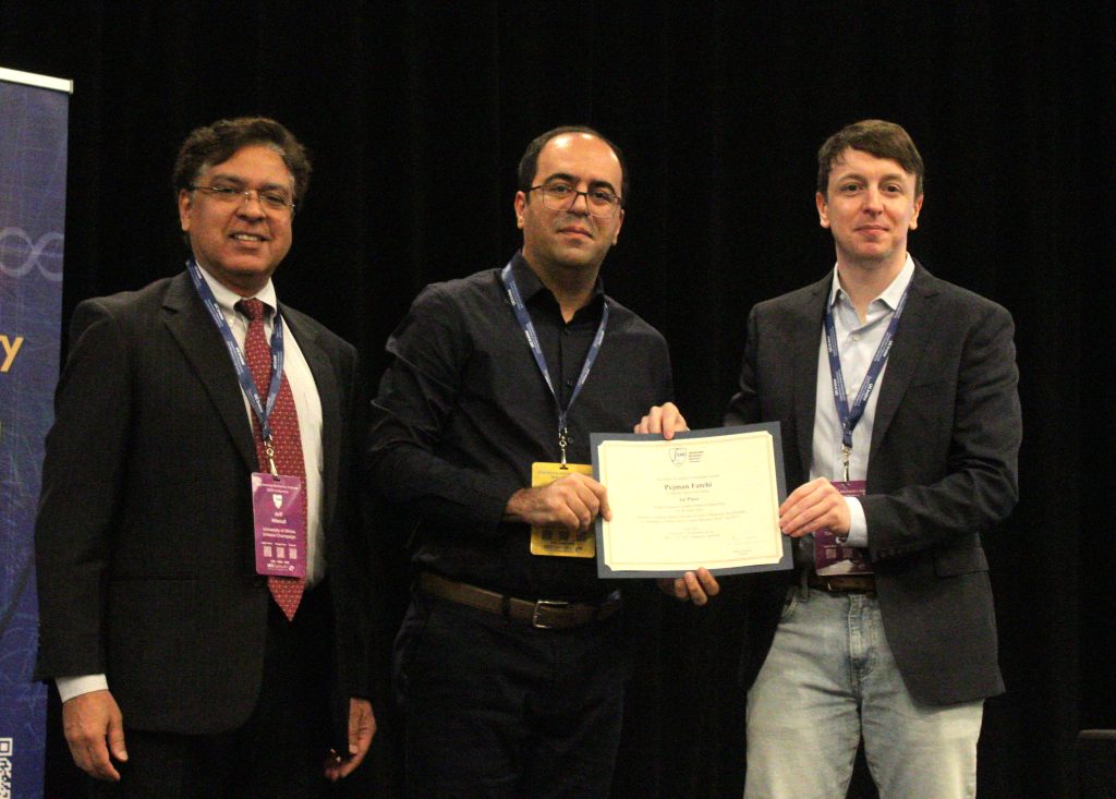 Pejman receives certificate from two men standing on each side.