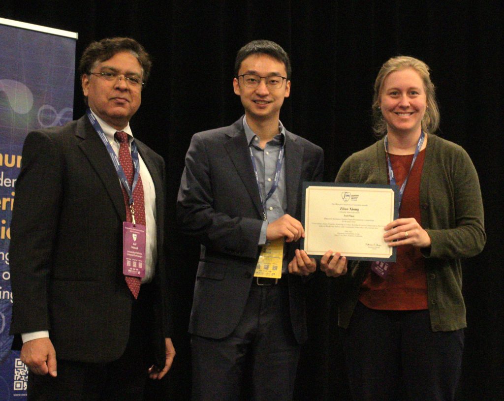 Student receives certificate from man and woman standing on each side.