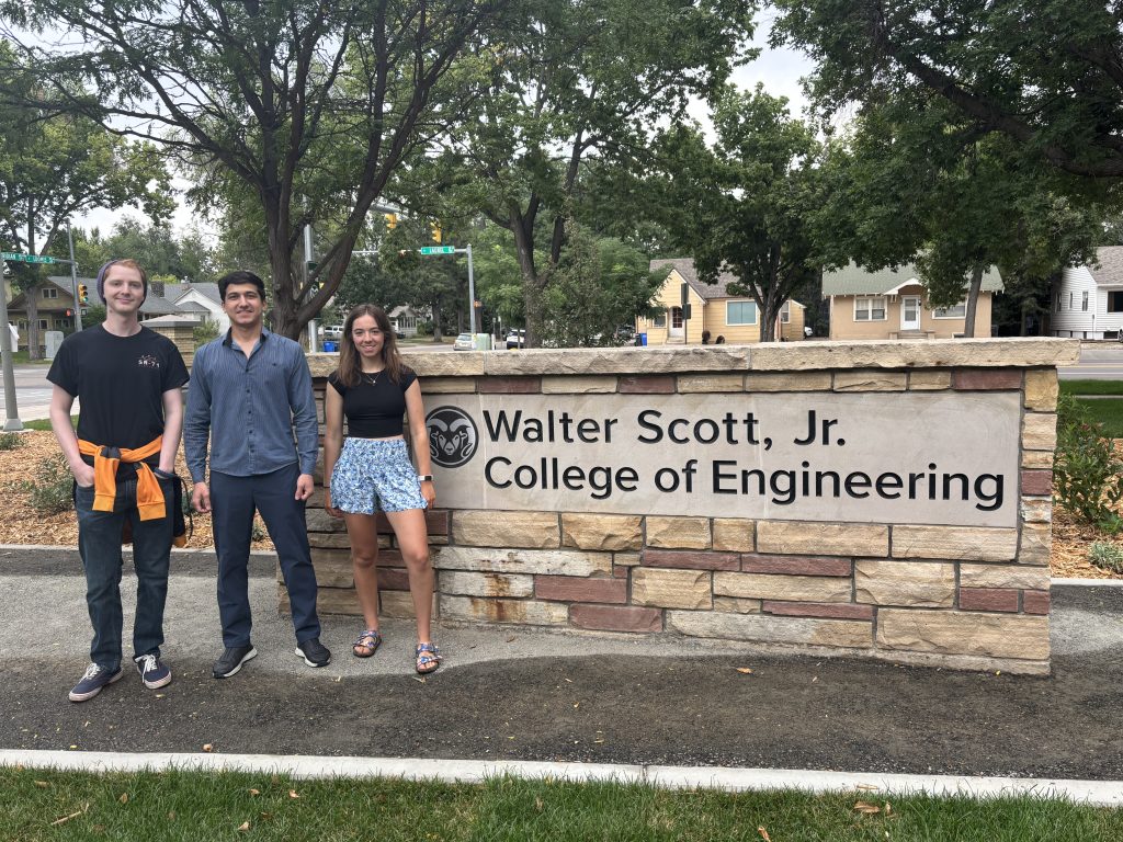 Students standing by brick sign that reads "Walter Scott, Jr. College of Engineering".