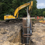 Yellow construction crane hovers over metal structure in crevice.