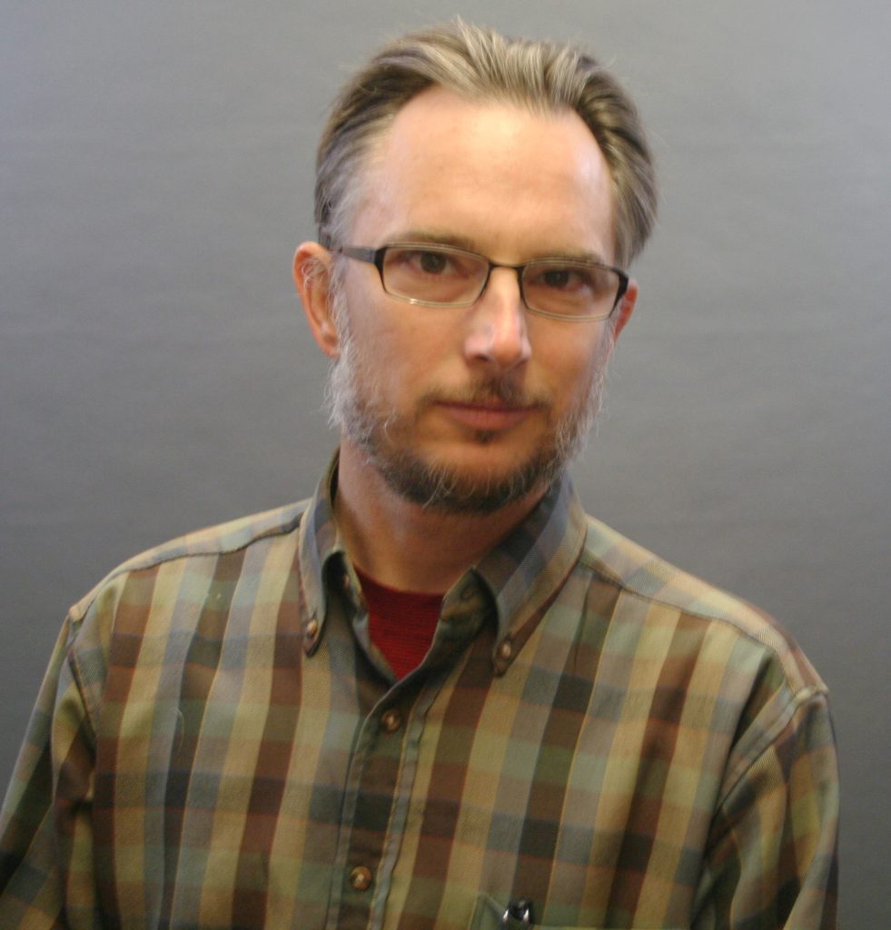 Portrait of man in green plaid shirt.