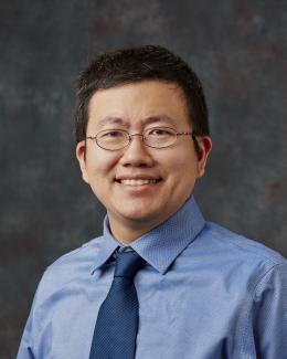 Portrait of man in glasses with blue shirt and tie.