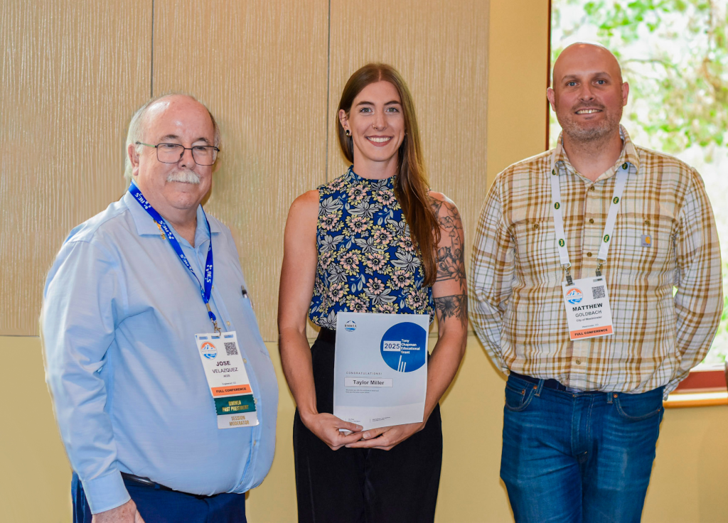 Taylor Miller holding award standing between two men.