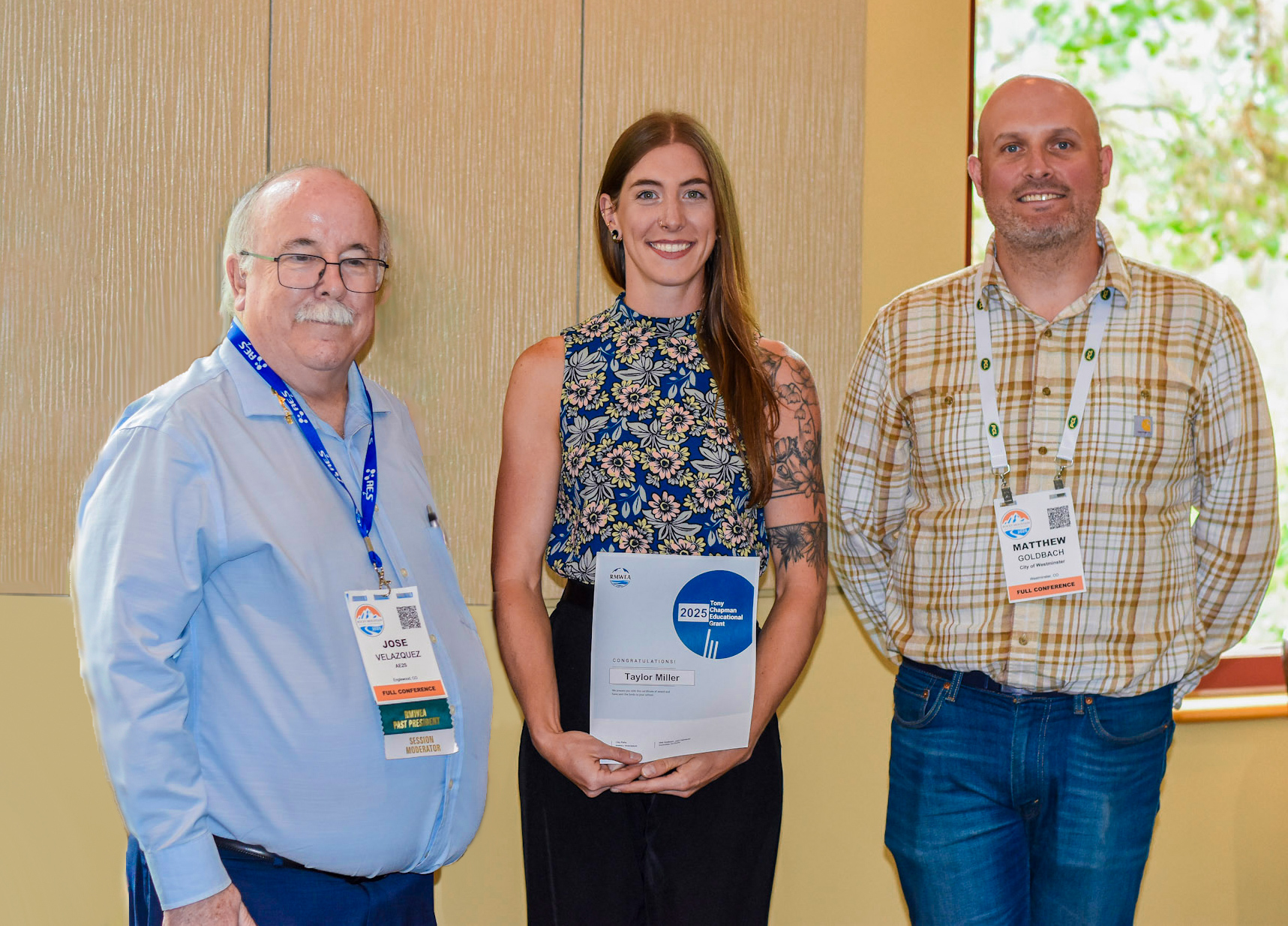 Taylor Miller holding award standing between two men.