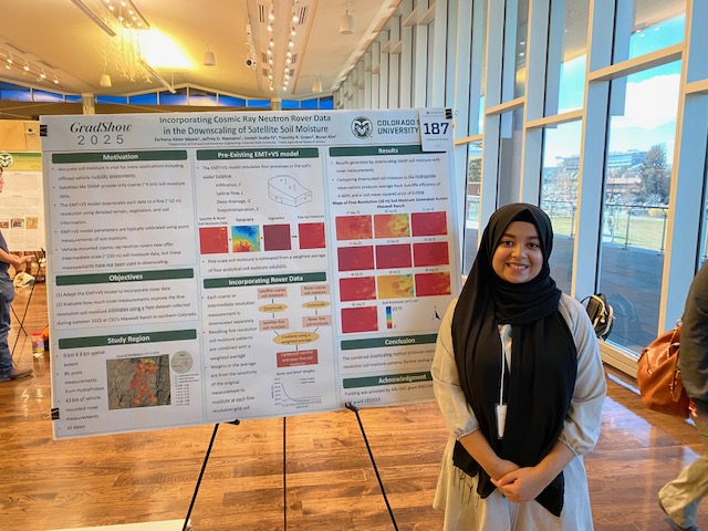 Woman in head covering stands at research poster.