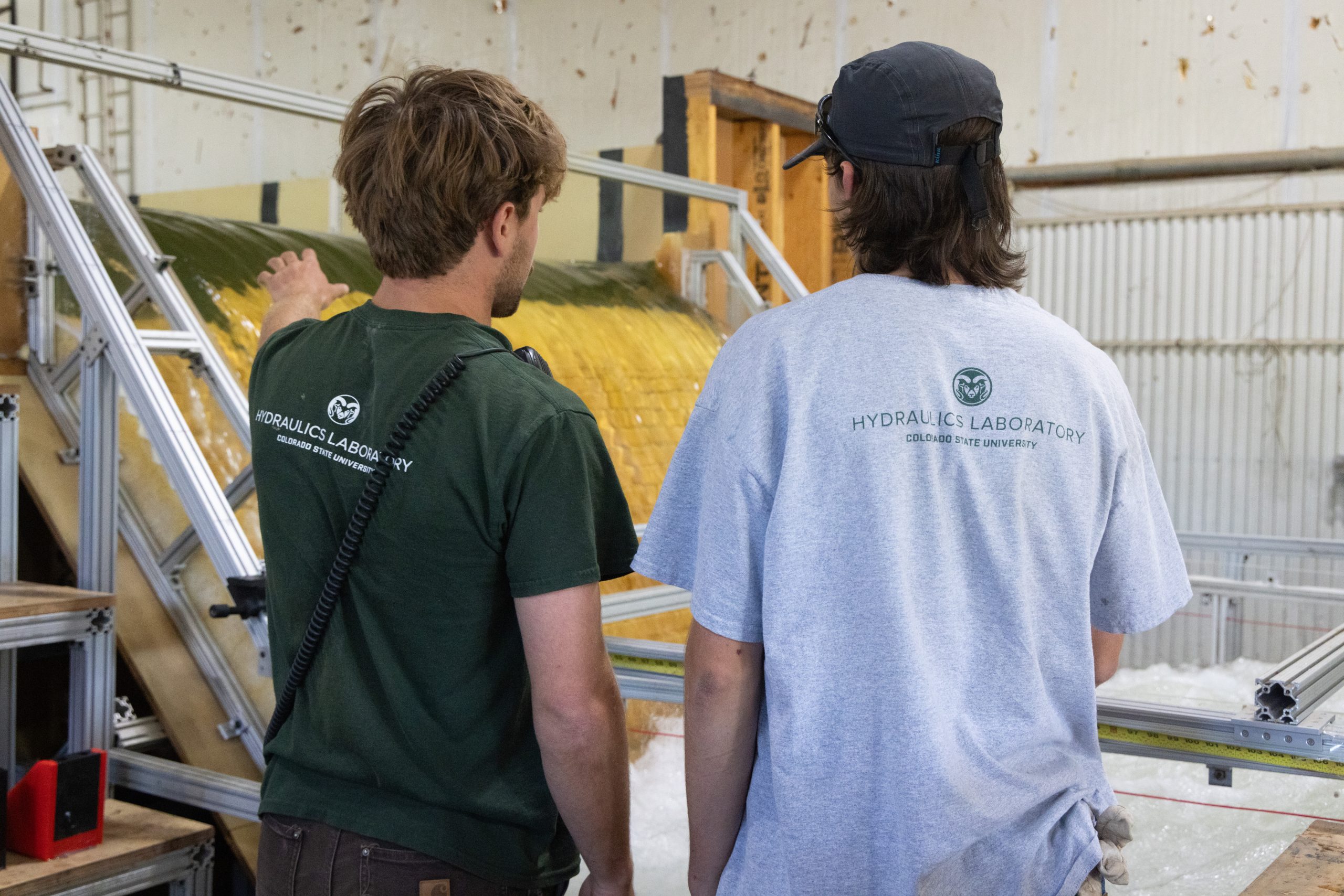 Two students discuss hydraulic structure with the back of the shirts reading "Hydraulics Laboratory".