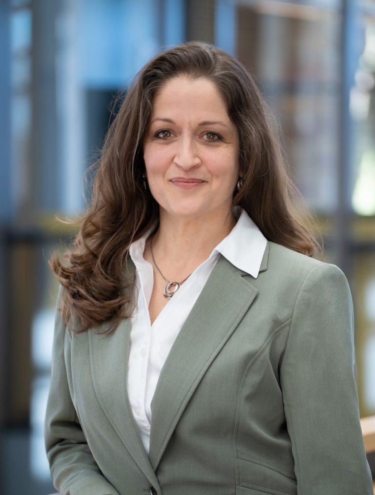 Environmental portrait of woman in green jacket and white shirt.