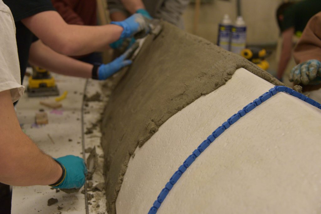 Close up of foam canoe mold half covered in concrete.