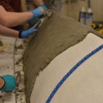 Close up of foam canoe mold half covered in concrete.