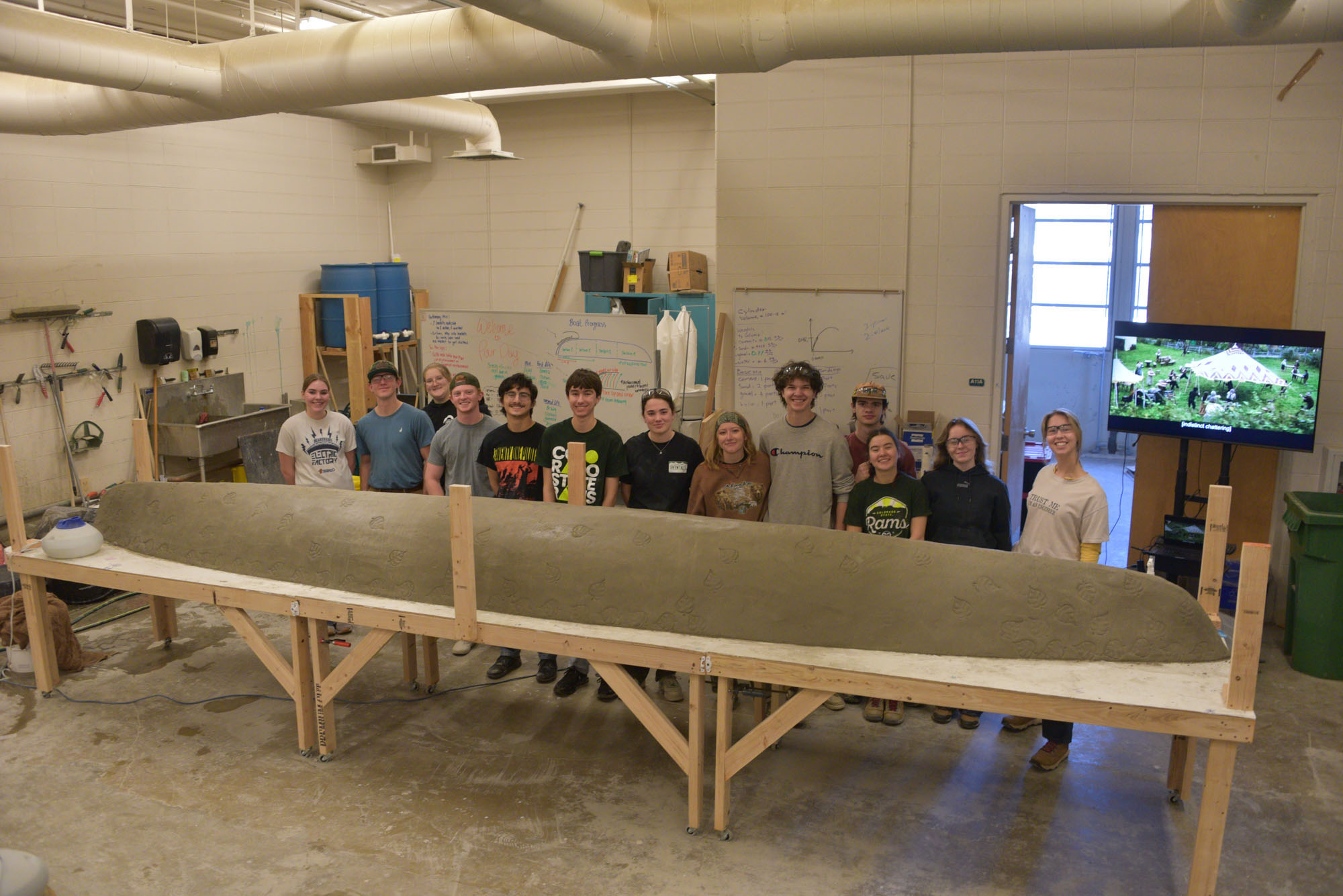 Group of students poses for photo with concrete canoe.