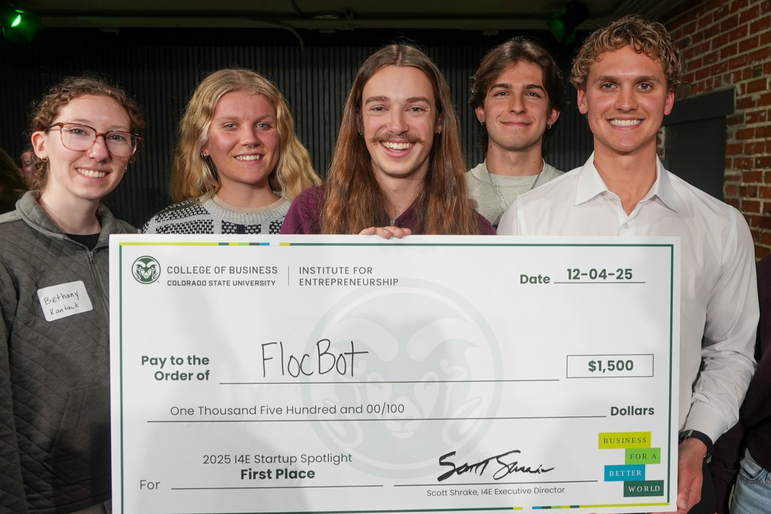 Group of students hold large check for $1,500 made out to "FlocBot".