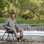 Man sitting in chair in river.