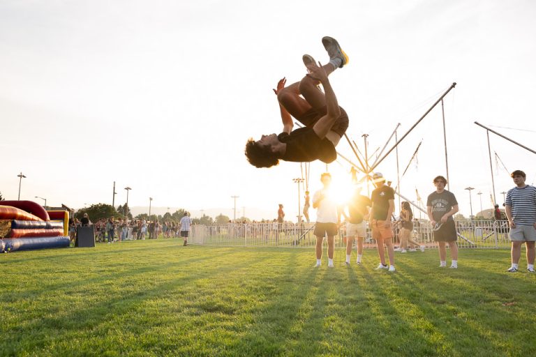 Student doing backflip in air with sunset in background