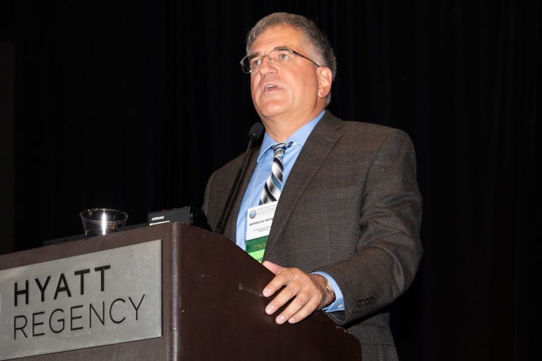 Photo of Dr. Notaros at podium giving address