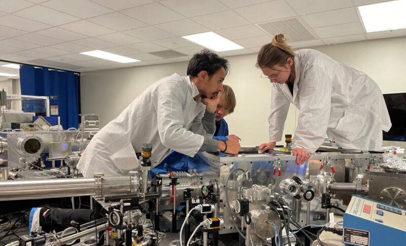 Three researchers working on large laser equipment