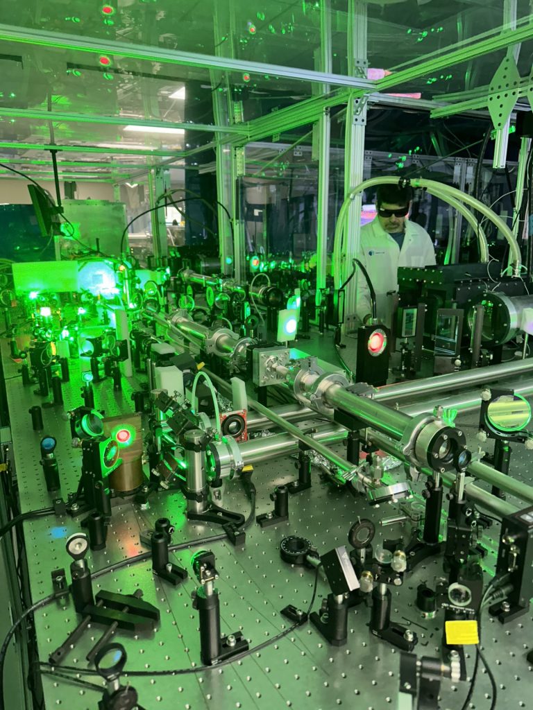 Research Scientist standing in center of large laser equipment in lab