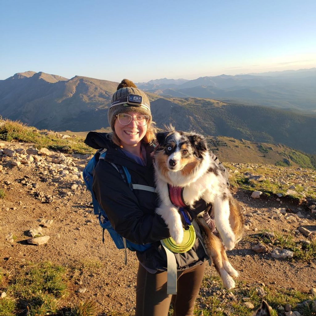 Woman hiker on a mountain top holding her dog