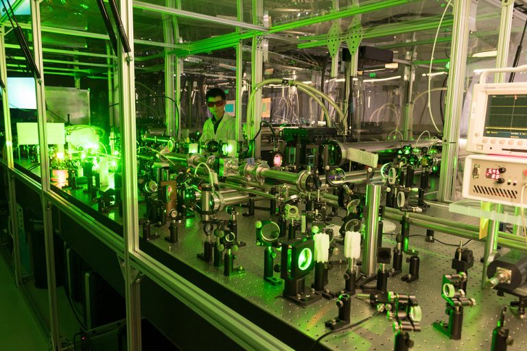 Dramatic photo of researcher in lab with large laser equipment
