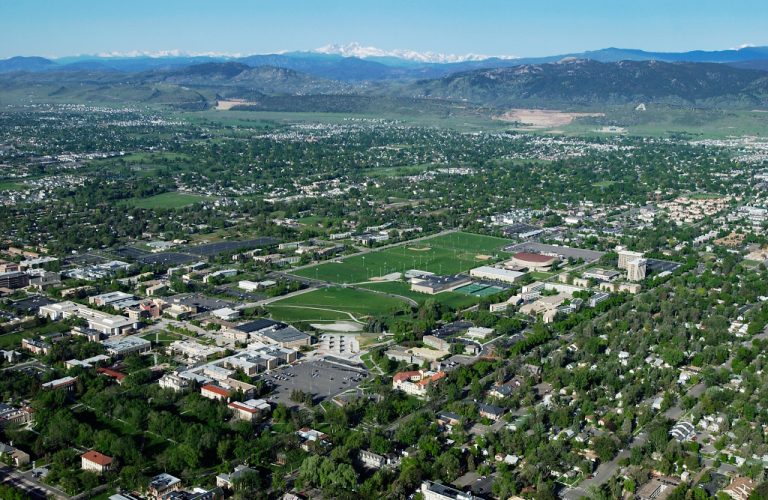 Aerial view of campus buildings, with landscape and mountains in background taken from a drone