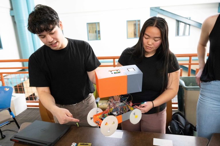 Two students working on colorful car as an engineering project