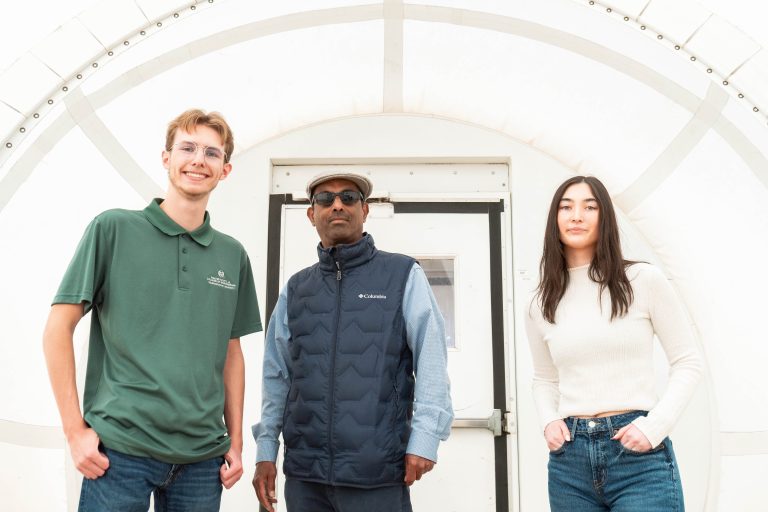 Prof. Chandra stands between one male and one female student