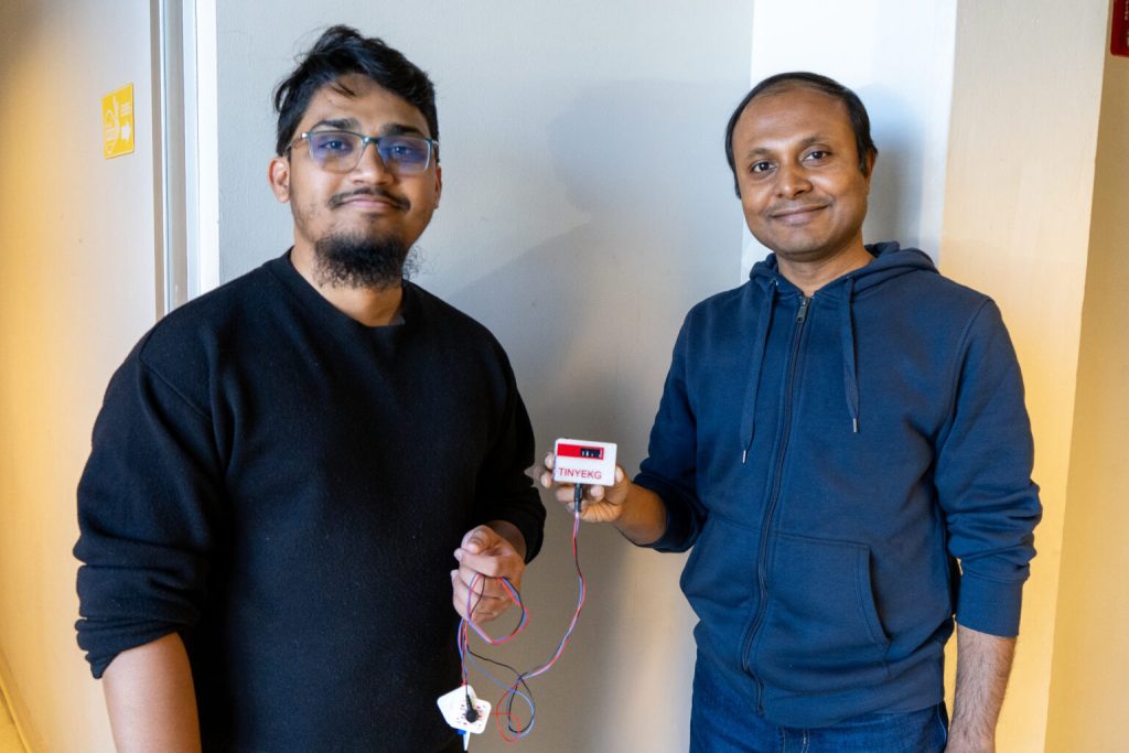 Two men holding tiny EKG device