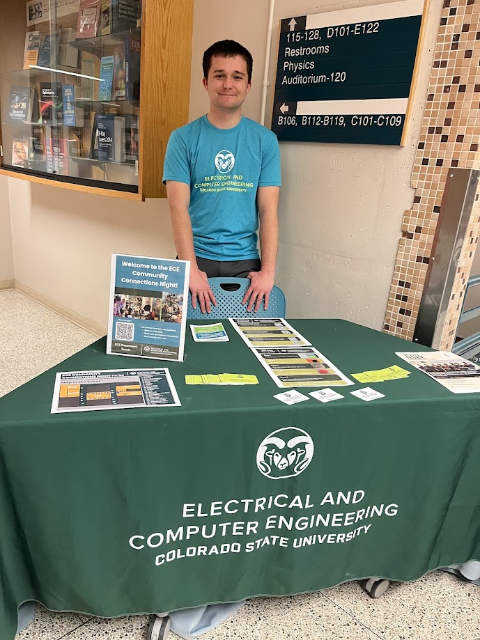 Male student stands in front of display table