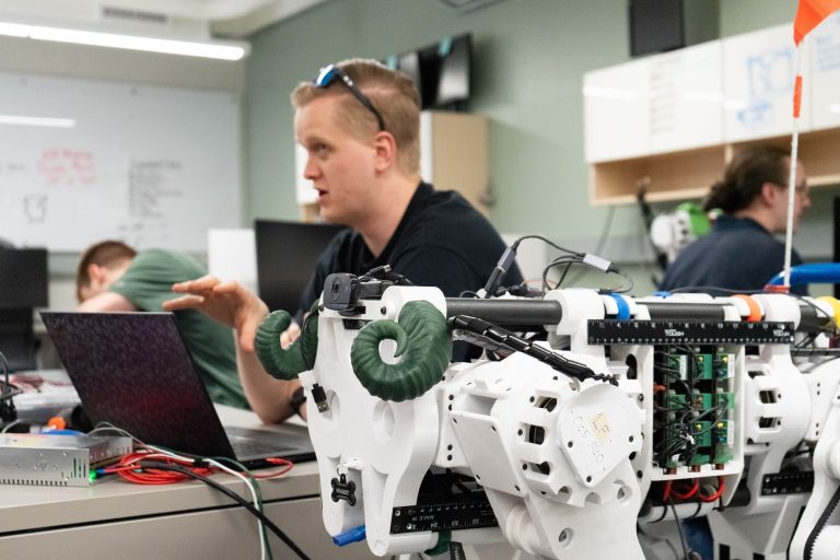 student sits behind robot