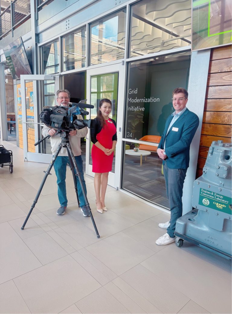 Three people stand behind news camera