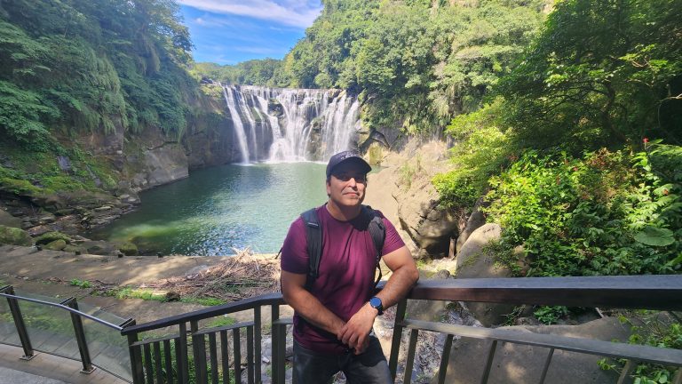 Man stands in front of waterfall
