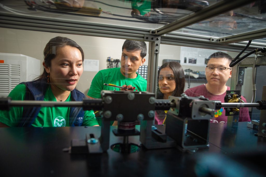 three people peer into device