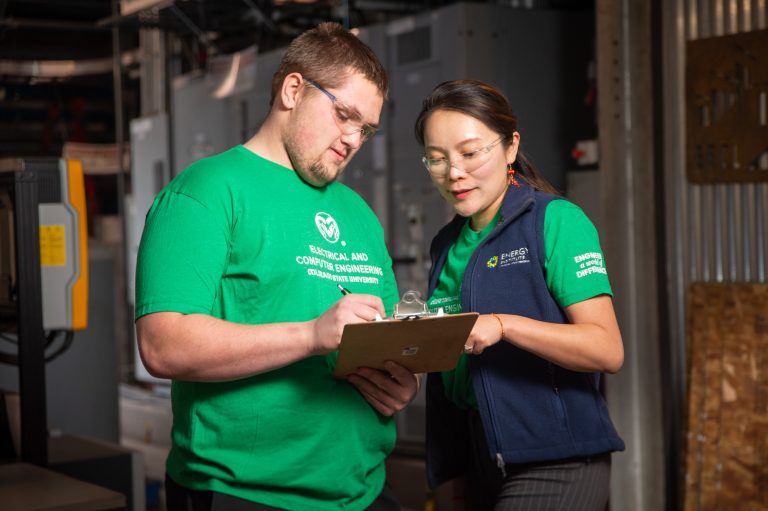 Zongjie Wang stands next to student with clipboard
