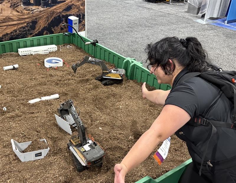 Dixie Poteet with a construction demonstration. Demonstration includes small construction vehicles and buildings in a modeled dirt pit.