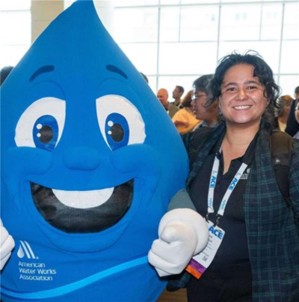 Dixie Poteet a PhD student in the lab standing with the water drop mascot at a conference