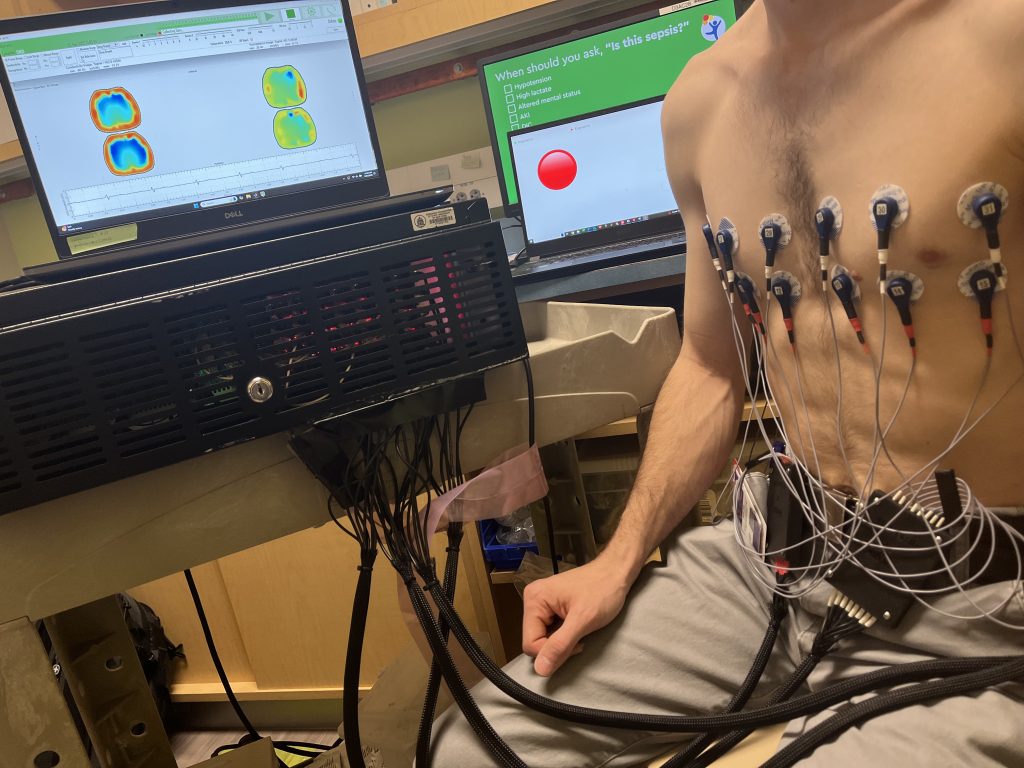 An image displaying the Act 5 EIT system in action. A chest reconstruction is visible on the screen, and two rows of electrodes are placed around a man's torso.