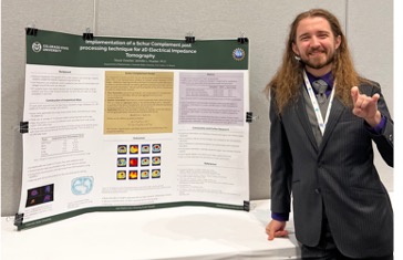 Lab member Trevor Overton poses with his EIT poster at the Joint Mathematics Meeting.