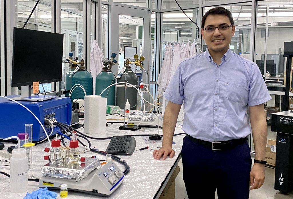 Dr. Reza Nazemi stands next to his lab equipment.