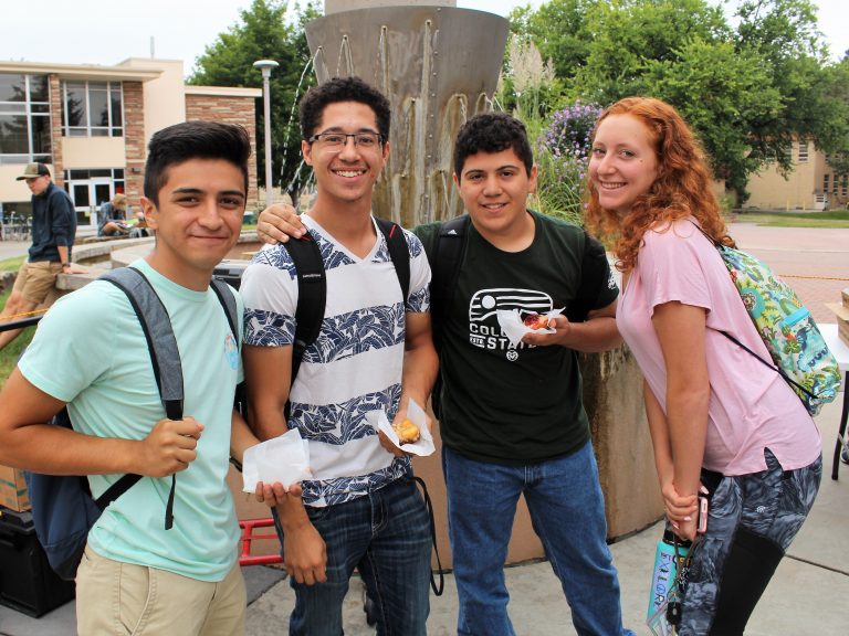 A group of students posing for a picture, some have food in their hands.
