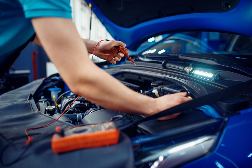 A person uses a volt meter on an electric car