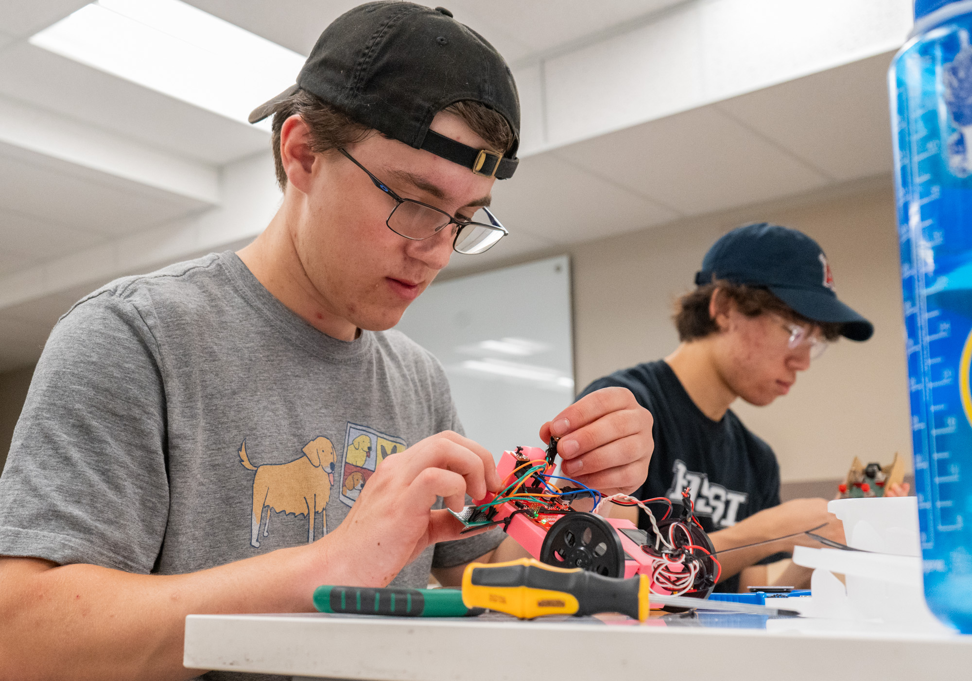 A male student is constructing a remote control car out of wire and 3-D printed material.